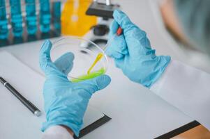 Female researchers are experimenting with pipette dropping a sample into a test tube in an experiment research in laboratory.. photo
