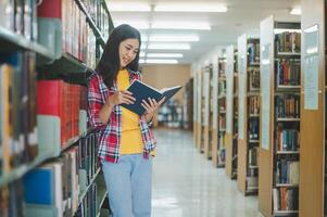 Students are reading and looking for books to study, make reports, find useful information on the bookshelves in the library. Concept of reading, learning and intelligence. photo