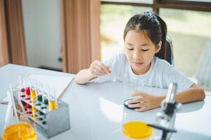 little scientist looking through a microscope and test tubes filled with chemicals for learning about science and experiments. photo