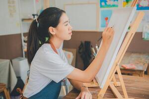 Art student drawing with watercolor painting on canvas doing some art projects on studio workshop photo
