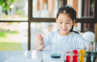 little scientist looking through a microscope and test tubes filled with chemicals for learning about science and experiments. photo