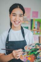 Portrait of Art student smiling happily while with watercolor painting on canvas doing some art projects on studio workshop photo