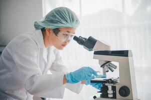 Female researchers are experimenting with pipette dropping a sample into a test tube in an experiment research in laboratory.. photo