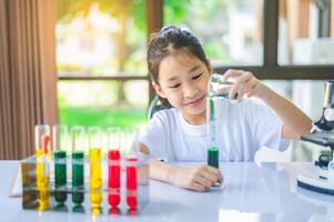 little scientist looking through a microscope and test tubes filled with chemicals for learning about science and experiments. photo