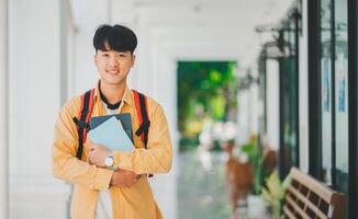 Happy smiling student with book in hand on campus while going to study for learning. photo