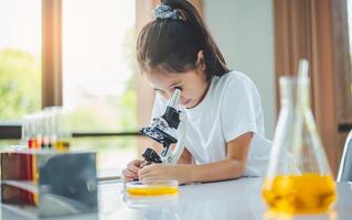 little scientist looking through a microscope and test tubes filled with chemicals for learning about science and experiments. photo
