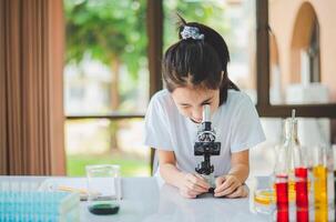 little scientist looking through a microscope and test tubes filled with chemicals for learning about science and experiments. photo