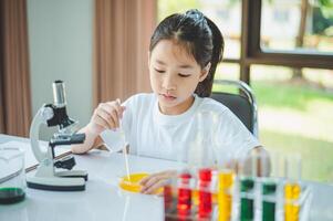 little scientist looking through a microscope and test tubes filled with chemicals for learning about science and experiments. photo