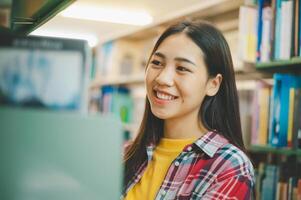 Female college students looking for books to study, make reports, find useful information on bookshelves in the library. Concept of reading, learning and intelligence. photo