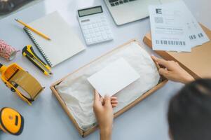 Closeup small business owners online Prepare to package products for delivery to customers according to their orders with a blank white label or business card to write a message. photo