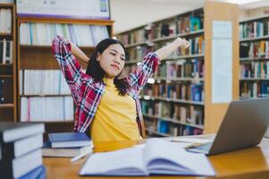 Students are relaxing after working on their laptops and searching for books to study, make reports, find useful information in the university room. photo