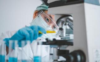 Female researchers are experimenting with pipette dropping a sample into a test tube in an experiment research in laboratory.. photo