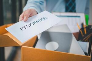 Hand holding a resignation envelope After resigning from work to find a new job , was fired by the company or when the employment contract expires, resulting in being unemployed photo