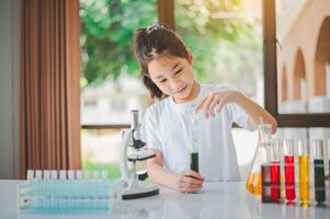 little scientist looking through a microscope and test tubes filled with chemicals for learning about science and experiments. photo