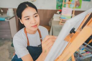 Art student drawing with watercolor painting on canvas doing some art projects on studio workshop photo