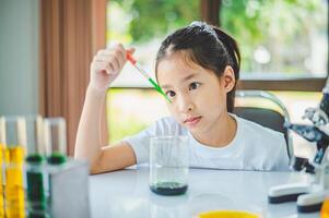 little scientist looking through a microscope and test tubes filled with chemicals for learning about science and experiments. photo
