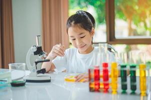 little scientist looking through a microscope and test tubes filled with chemicals for learning about science and experiments. photo
