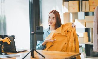 SME owner using the smartphone and tablet for recording . vlog and live stream at her shop,SME business concept, online shopping. photo
