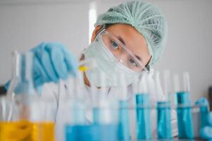 Female researchers are experimenting with pipette dropping a sample into a test tube in an experiment research in laboratory.. photo