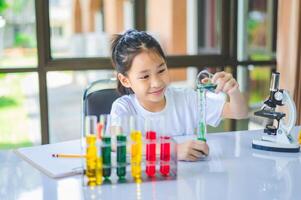 little scientist looking through a microscope and test tubes filled with chemicals for learning about science and experiments. photo