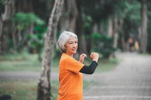 white-haired elderly person exercising in the park early in the morning. photo