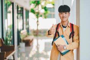 Happy smiling student with book in hand on campus while going to study for learning. photo
