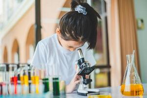 little scientist looking through a microscope and test tubes filled with chemicals for learning about science and experiments. photo