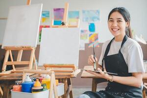 Portrait of Art student smiling happily while with watercolor painting on canvas doing some art projects on studio workshop photo