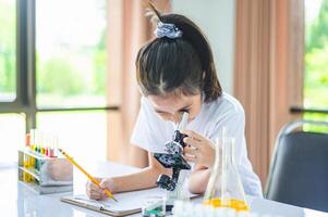 little scientist looking through a microscope and test tubes filled with chemicals for learning about science and experiments. photo