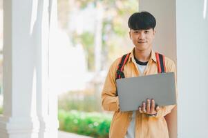Happy smiling student with book in hand on campus while going to study for learning. photo