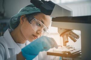 Female researchers are experimenting with pipette dropping a sample into a test tube in an experiment research in laboratory.. photo