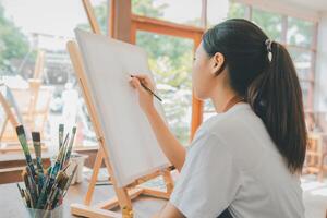 Art student drawing with watercolor painting on canvas doing some art projects on studio workshop photo