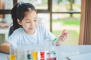 little scientist looking through a microscope and test tubes filled with chemicals for learning about science and experiments. photo