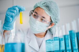 Female researchers are experimenting with pipette dropping a sample into a test tube in an experiment research in laboratory.. photo