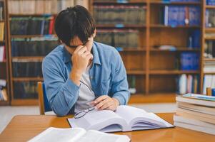 Students feel tired and stressed after working on their laptops and looking for books to study, make reports, find useful information in the university room. photo