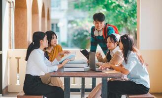 group of students young university students consulting doing homework, cooperating research plan Discuss concepts and strategies. Prepare presentations on laptops and tablet computers. photo