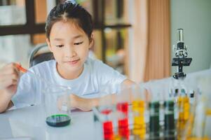 little scientist looking through a microscope and test tubes filled with chemicals for learning about science and experiments. photo