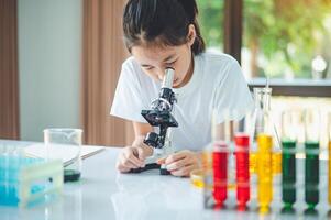 little scientist looking through a microscope and test tubes filled with chemicals for learning about science and experiments. photo