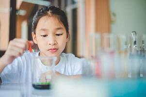 little scientist looking through a microscope and test tubes filled with chemicals for learning about science and experiments. photo