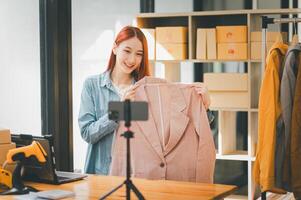 SME owner using the smartphone and tablet for recording . vlog and live stream at her shop,SME business concept, online shopping. photo