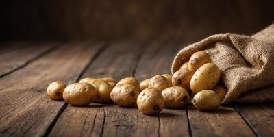 Potatoes spilling from a burlap sack on rustic wooden planks. photo