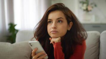 Bored thoughtful Caucasian female tired woman girl client user boredom typing message chatting using mobile phone scrolling social media boring online app thinking problem solution at home living room photo