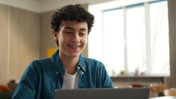 Caucasian man male student guy boy schoolboy pupil with toothy dental braces in class lesson school university studying learning education study learn using laptop computer e-learning knowledge online photo