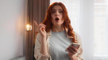 Pensive Caucasian woman confused girl lady thinking problem lost in thought at home hold mobile phone puzzled female idea raise finger gesture find solution answer type text sms chat online brainstorm photo