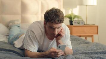Serious Caucasian man bed using mobile phone smartphone guy male technology pensive problem frown error rejection fail broken gadget spam connection notification stressful worry wrong trouble banking photo
