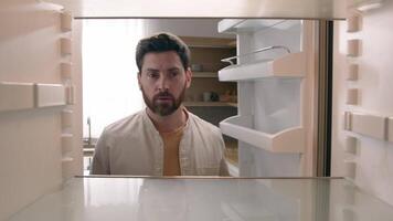 POV point of view from inside refrigerator Caucasian hungry man adult sad upset disappointed male guy looking for good twice open empty fridge no food without products crisis delivery supermarket photo