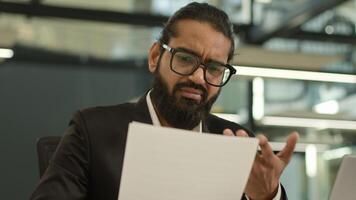 Arabian Muslim business man Indian businessman employer entrepreneur manager confused with papers and laptop in office problem paperwork bad result talking call working with documents failure photo