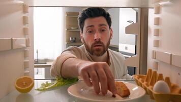 POV point of view from inside refrigerator Caucasian hungry adult man need meal products empty fridge with junk half lemon, lettuce leaf, one egg eating bread crumbs food delivery unemployment crisis photo