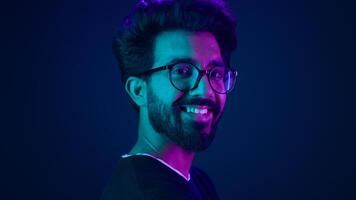 Portrait Indian man standing in profile side view turn to camera smiling toothy happy guy developer coding smile computer internet technology hacker Arabian male neon ultraviolet high-tech cyberspace photo