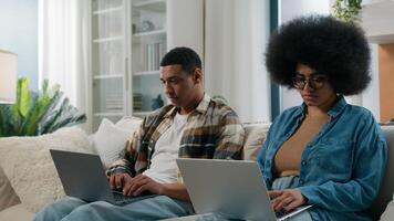 African American gadget addict couple internet addicted husband and wife social media virtual game addiction man and woman working using two laptops play with computers at home relationship problem photo